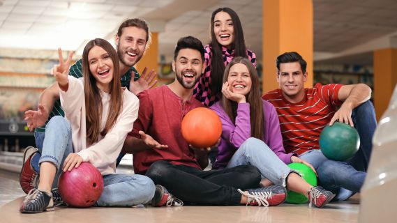 Bowling balls lined up in front of colorful bowling alley lanes