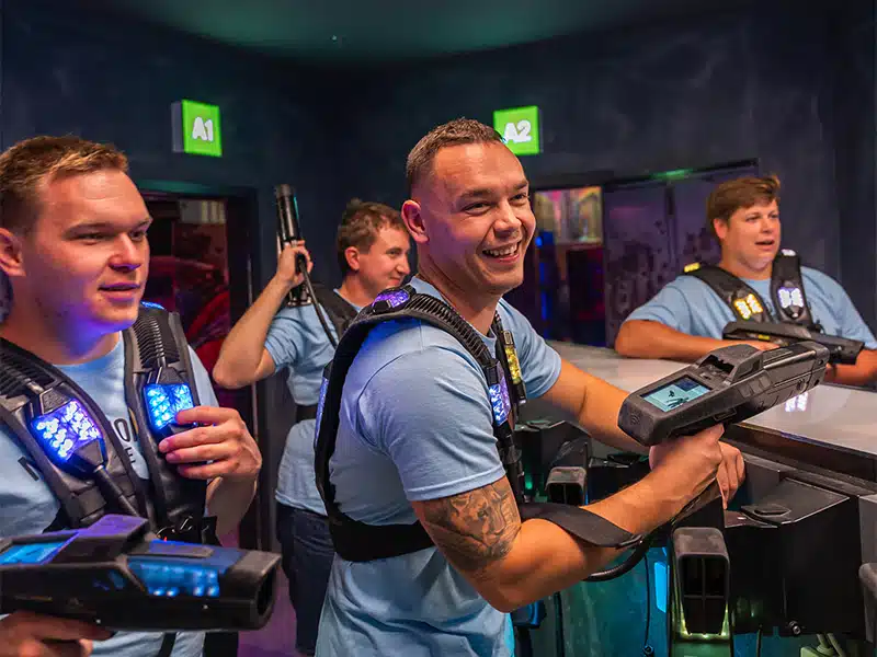 People playing laser tag in a neon-lit multi-level arena